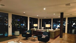 A spacious living area with a sofa set, two armchairs, a coffee table, and a view of the city at night. - The Trendy Den  Music & Nightlife Nearby (Dallas)