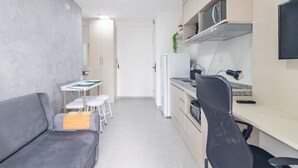 Un espacio habitable compacto con kitchenette, zona de comedor y zona de estar.