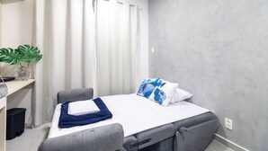 Una habitación pequeña con cama, un escritorio y una planta en maceta.