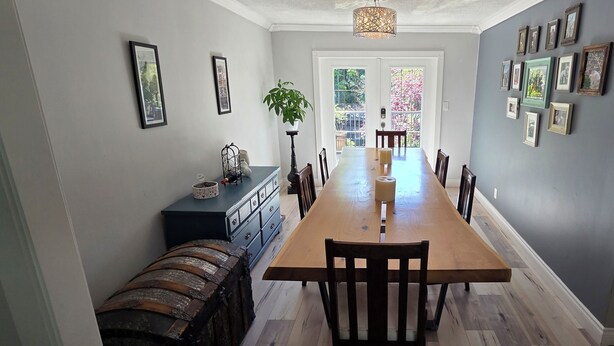 A dining area with a long wooden table, chairs, a bench, and a potted plant.
