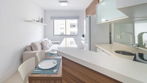 Eine moderne Küche mit Einbaukühlschrank, ein Essbereich mit Tisch für Zwei und ein Fenster für natürliches Licht.