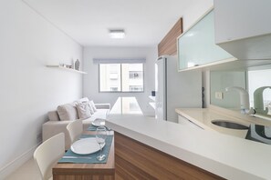 A modern kitchen with a built-in refrigerator, a dining area with a table set for two, and a window providing natural light. - OF1799_902 (São Paulo)