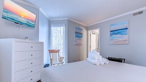Ein Schlafzimmer mit einem Bett, einem Schminktisch, einem Sessel und zwei Bildern an den Wänden.