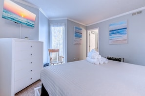 Ein Schlafzimmer mit einem Bett, einem Schminktisch, einem Sessel und zwei Bildern an den Wänden.