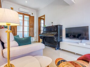Un salon avec un canapé, un téléviseur, un piano et une lampe.