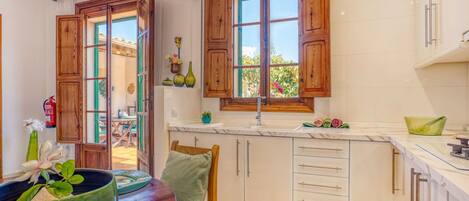 Una cocina con armarios de madera, una mesa de comedor con sillas y una ventana con vistas a la vegetación.