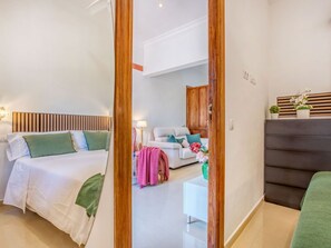 Une chambre d’hôtel moderne dotée d’un grand lit, d’un coin salon séparé et offrant une vue sur l’extérieur grâce à une porte ouverte.