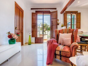 A spacious living area with a sofa, a dining table, and a view through open wooden doors to an outdoor garden. - Casa Vileta by Interhome (Vileta)