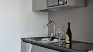Eine moderne Küche mit Einbauofen, Dunstabzugshaube aus Edelstahl und einer Weinflasche auf der Arbeitsplatte.