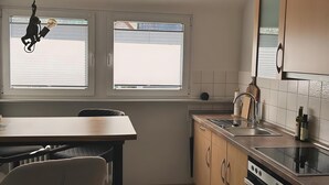 Eine moderne Küche mit Essbereich, einem eingebauten Backofen und einem Fenster mit Jalousien.