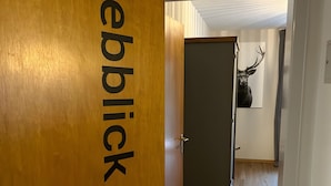 Ein Flur mit einer Holztür mit der Aufschrift 'Rebblick', einem Schlüsselbund und einem Bild von einem Reh an der Wand.