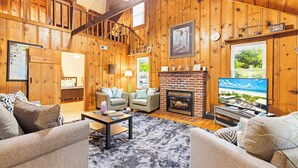 Ein Holzinnenraum mit Kamin, Fernseher und Sitzecke.