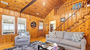 Ein Holzinterieur mit einer Couch, einem Sessel und einer Treppe.