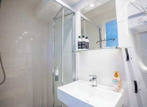 A modern bathroom with a glass shower enclosure, a white sink with a chrome faucet, and a mirror above the sink. - Hotel Nine Zandvoort - Room 1: 2 Adults, 2 Children only (Zandvoort)