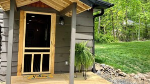 A log cabin with a wooden porch, a door with glass panels, and a welcome mat. - Unique, renovated, historic log cabin in charming Hendersonville (Hendersonville)