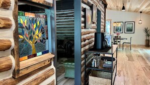 A log cabin interior with a wooden floor, a coffee machine, a sofa, and a wall-mounted shelf. - Unique, renovated, historic log cabin in charming Hendersonville (Hendersonville)