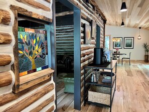 A log cabin interior with a wooden floor, a coffee machine, a sofa, and a wall-mounted shelf. - Unique, renovated, historic log cabin in charming Hendersonville (Hendersonville)