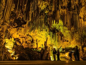 Eine Höhle mit Stalaktiten und Stalagmiten, beleuchtet durch künstliches Licht.