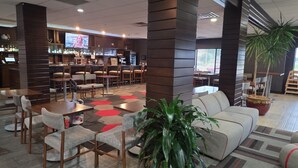 Un moderno vestíbulo con zona de bar, espacios de descanso y una gran planta.