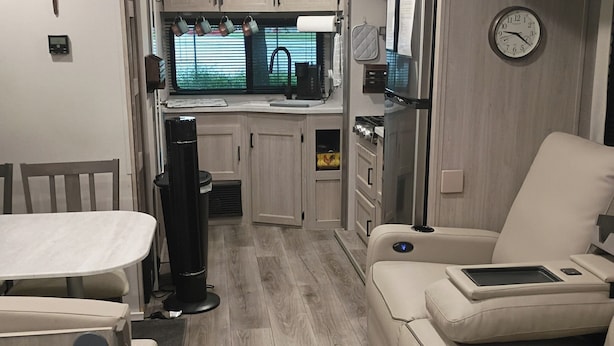 Un intérieur de camping-car compact comprenant un coin cuisine, un espace repas et un coin salon.