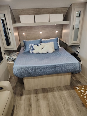 Une chambre à coucher avec un lit, une tête de lit, une table de chevet, une chaise et un plancher en bois.