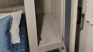 Une armoire en bois dotée d’une étagère coulissante, d’une tringle et d’une porte avec une poignée.