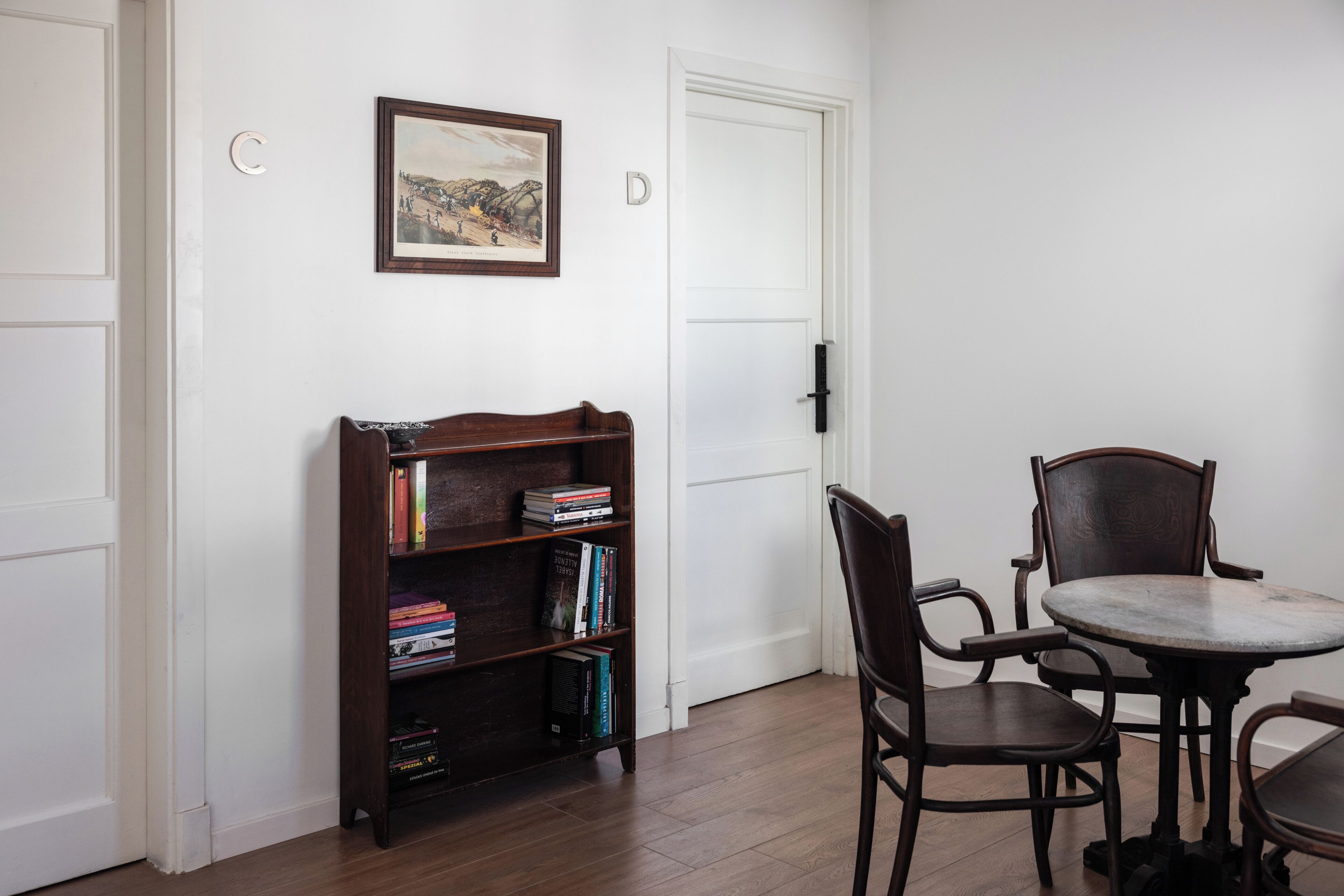 Une pièce avec une bibliothèque, une table à manger et des chaises, et une porte.