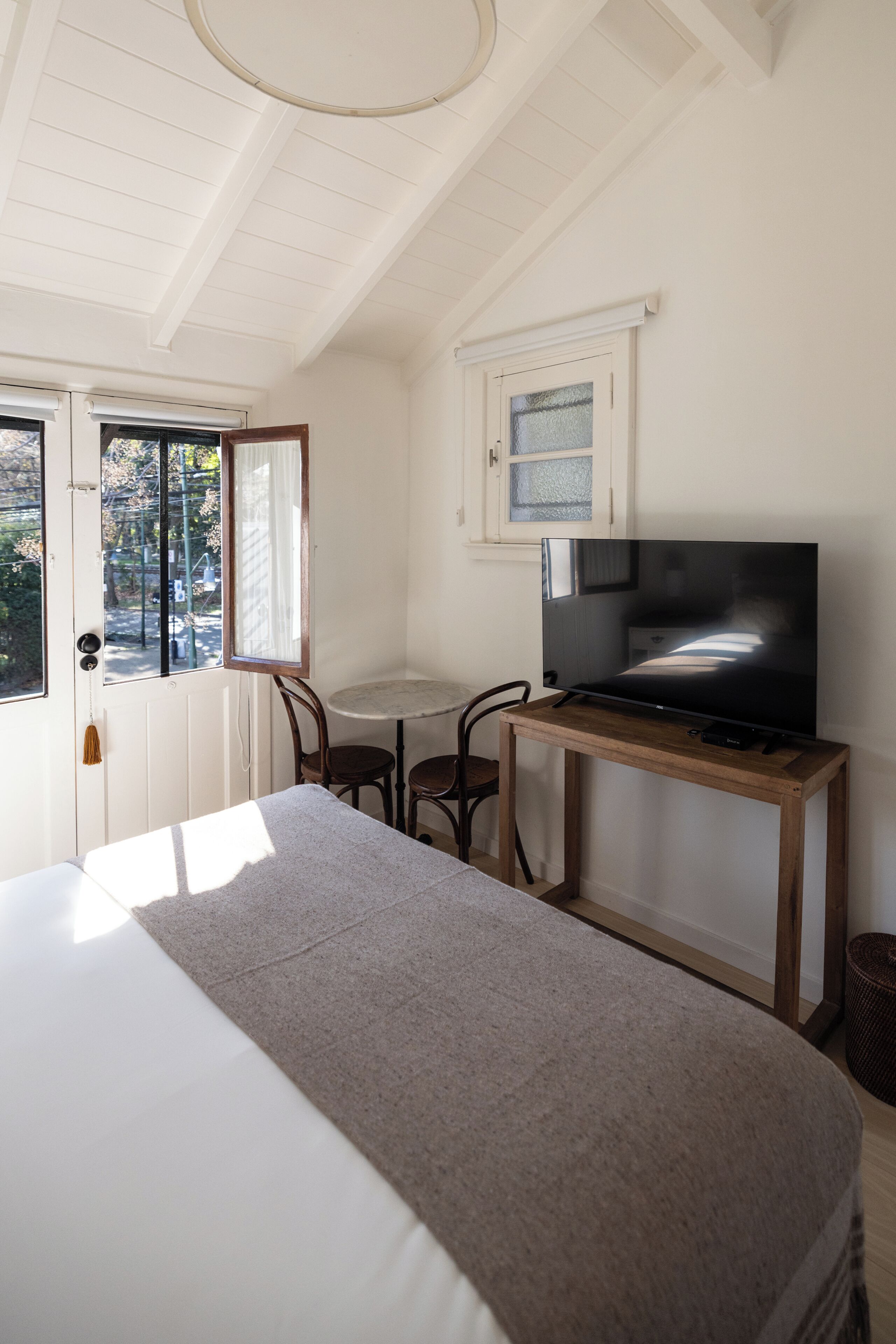 Una camera da letto con un letto, una televisione su un tavolino di legno, una sedia e una finestra.