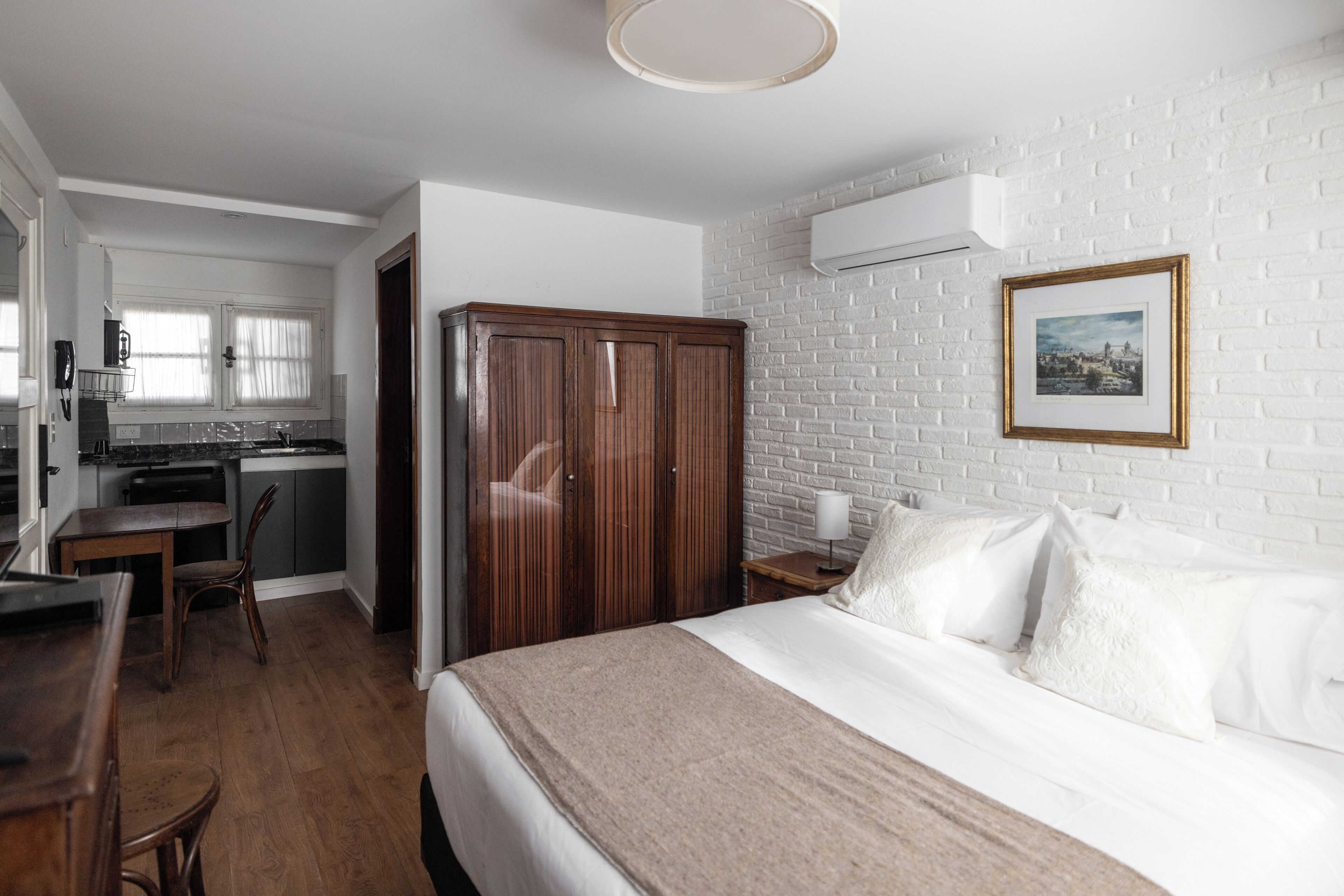A hotel room with a bed, a desk, a wardrobe, and a kitchenette.