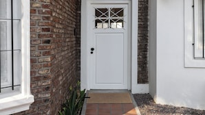 A white door with a window above it, set in a brick wall. - Acassuso Suites (Acassuso)