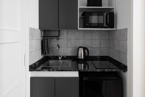 Una cuina amb taulell negre, un búllet d'acer inoxidable, un microones i un rentaplat.