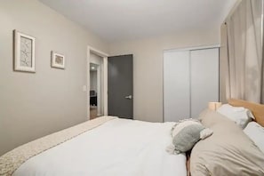 Ein Schlafzimmer mit einem Bett, einem Kleiderschrank und einer Tür zu einem anderen Raum.