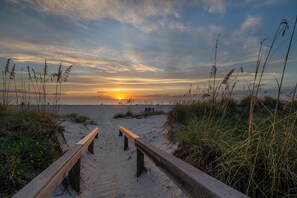 A wooden pathway leading to a beach with a sunset in the background. - 4BR Family Oasis - Heated Pool - Walk to Beach (St. Pete Beach)
