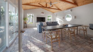 Un'ampia zona giorno con soffitto in legno, una TV, un divano e un tavolo da pranzo con sedie.