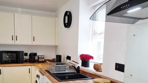 Una cocina moderna con armarios blancos, encimera de madera, horno empotrado, microondas y fregadero.