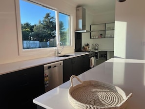 A modern kitchen with a large window, built-in cabinets, a dishwasher, and a woven basket on the counter.