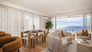 Un soggiorno moderno con un tavolo da pranzo in legno, divani e un'ampia finestra vista mare.