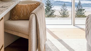 Una stanza con un'ampia finestra, un divano con una coperta, un tavolo in marmo e un vaso decorativo.