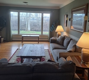 A living room with a large window, a sofa, a coffee table, and two lamps.