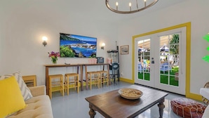 Een woonkamer met een houten tafel, een bank en een eethoek met stoelen.