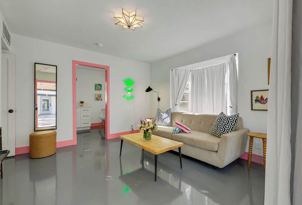 En moderne stue med sofa, sofabord og et spejl.