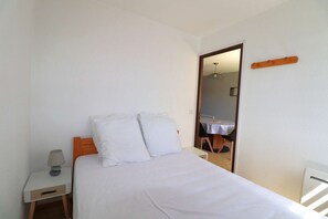 Ein Schlafzimmer mit einem Bett, einem Nachttisch, einer Lampe und einem Spiegel.