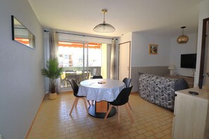 Ein Essbereich mit einem runden Tisch, Stühlen, einer Zimmerpflanze und einer Couch.