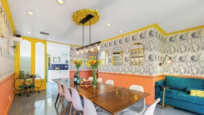 A dining area with a wooden table, white chairs, and a blue sofa. - Spirit of Sofia 12bd (Palm Springs)