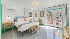A bedroom with a bed, bedside tables, a lamp, a mirror, and a view through a glass door. - Spirit of Sofia 12bd (Palm Springs)