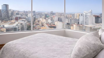 Quarto com uma cama grande, vista para a cidade e uma luminária de teto moderna.