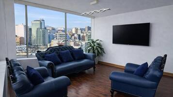 Uma sala de estar moderna com vista para a cidade, uma televisão de tela plana e sofás de couro.