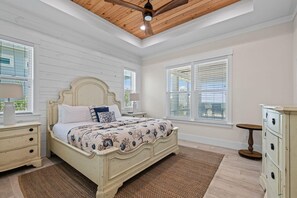 Ein Schlafzimmer mit Bett, Nachttischen, einem Schminktisch und einem Deckenventilator.
