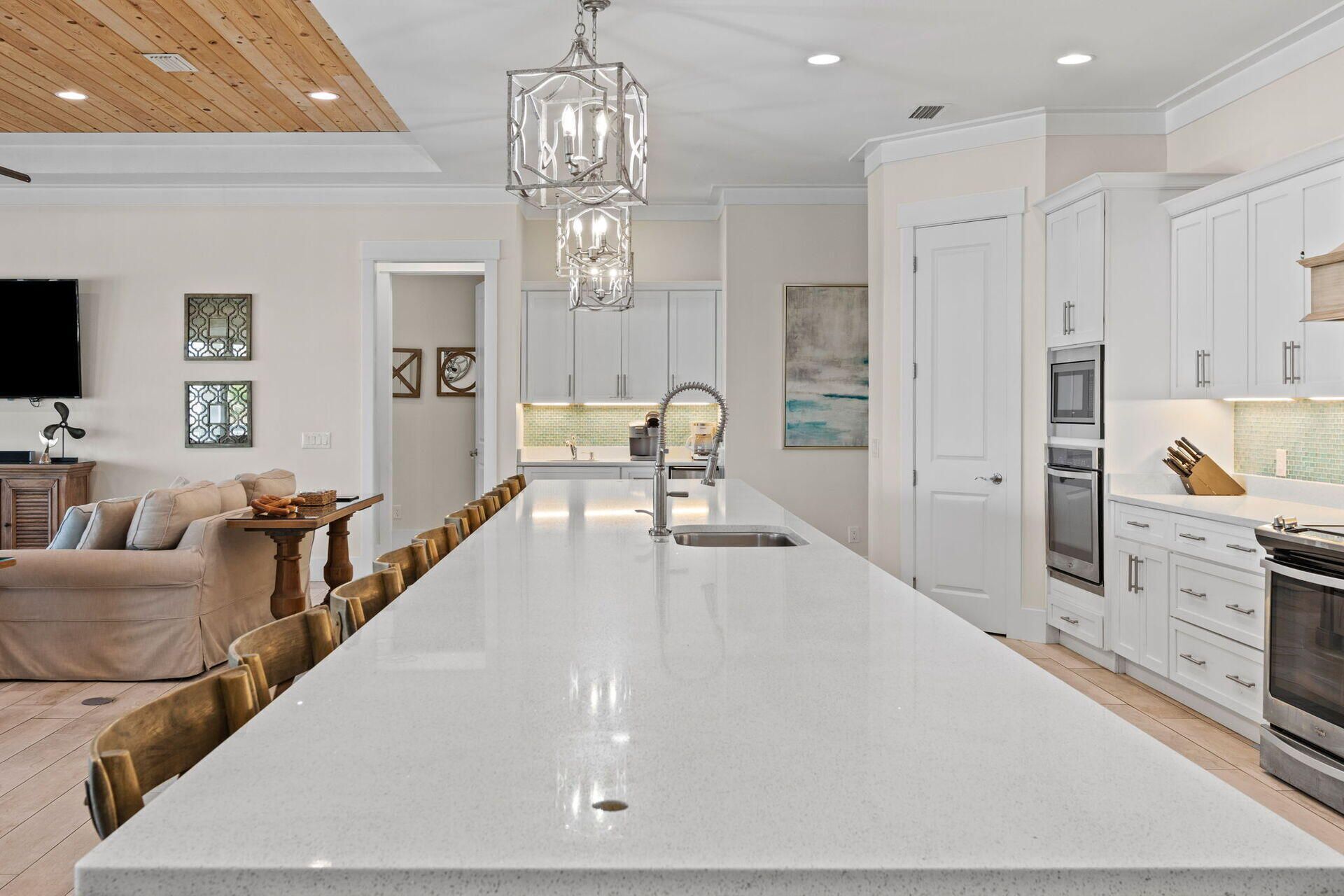 A modern kitchen with a central island, white cabinetry, and stainless steel appliances.