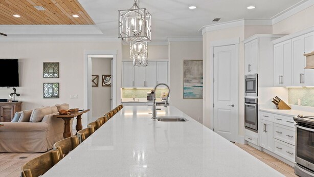 Una cocina moderna con una isla central, muebles de cocina blancos y electrodomésticos de acero inoxidable.